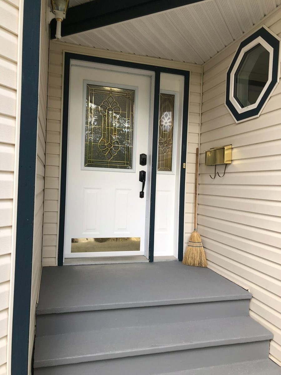 The same front entry after painting, white door with dark teal trim and grey concrete steps