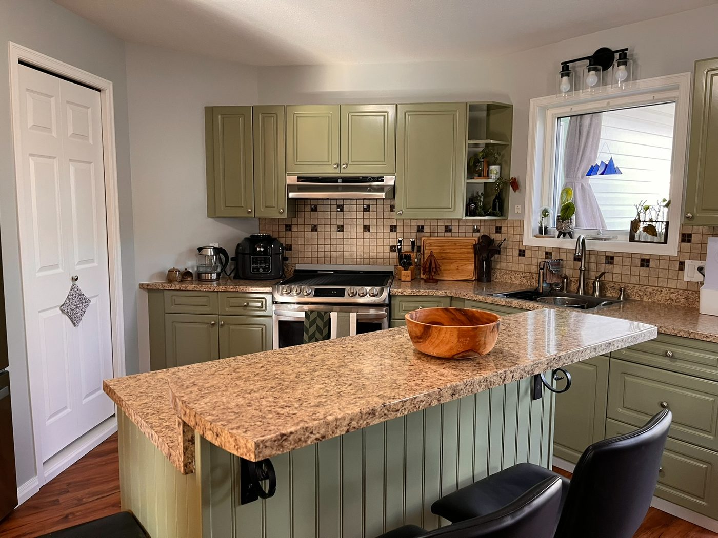 The same kitchen after refinishing, cabinets sprayed sage green with white trim