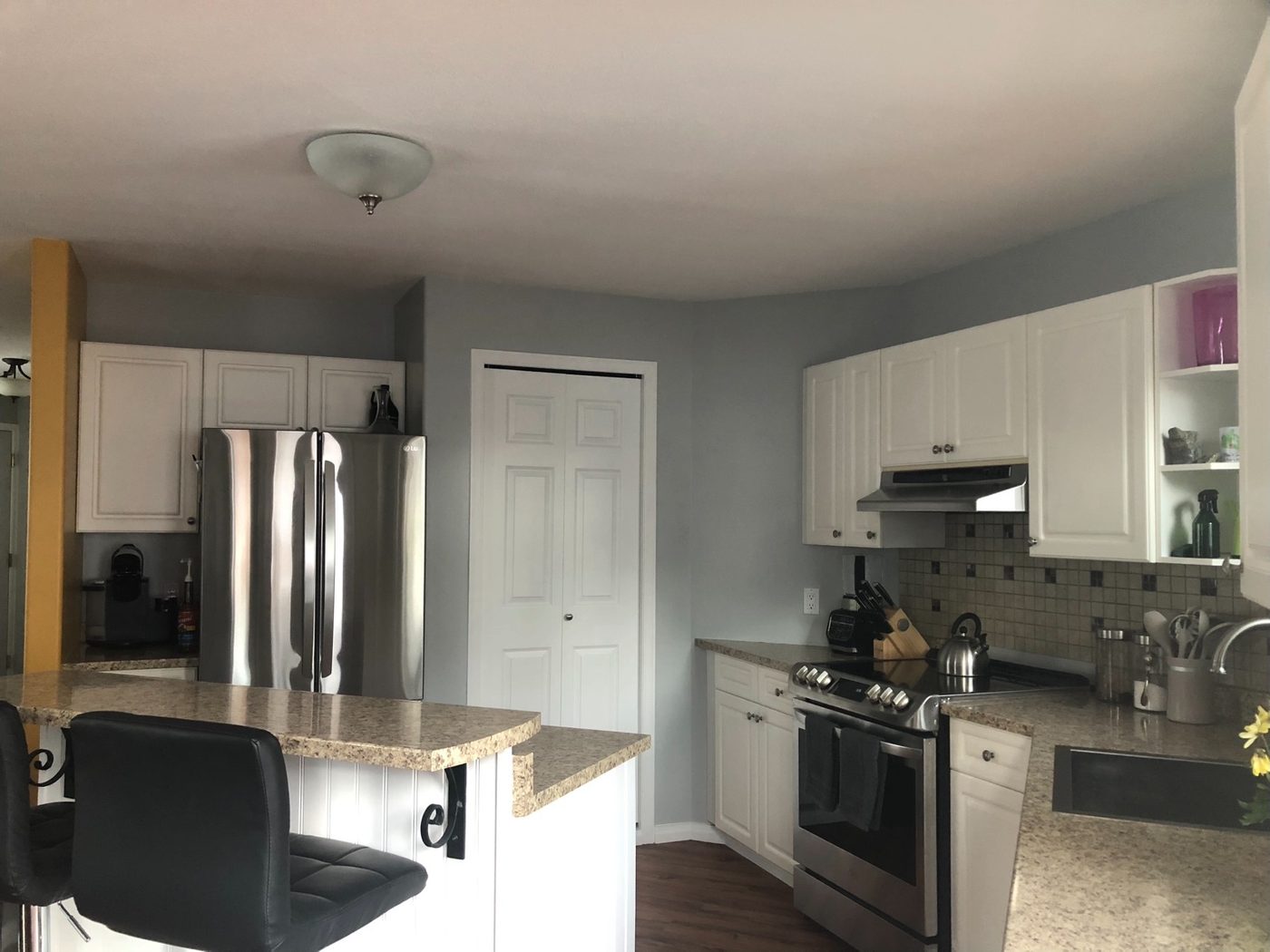 Kitchen with white cabinets and grey walls before refinishing, Whitehorse home